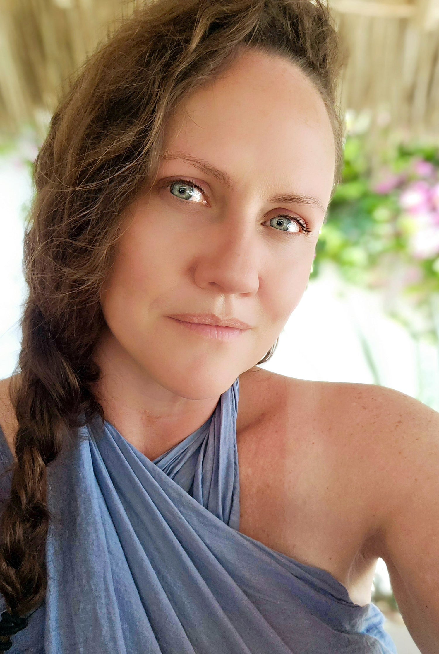 Woman wearing a light blue halter top with a blurred outdoor background